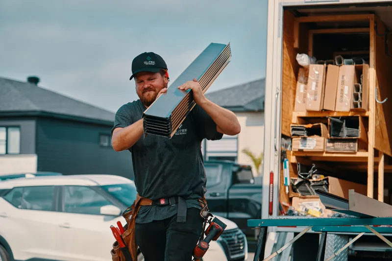 Installer carrying a new seamless aluminum gutter to the house